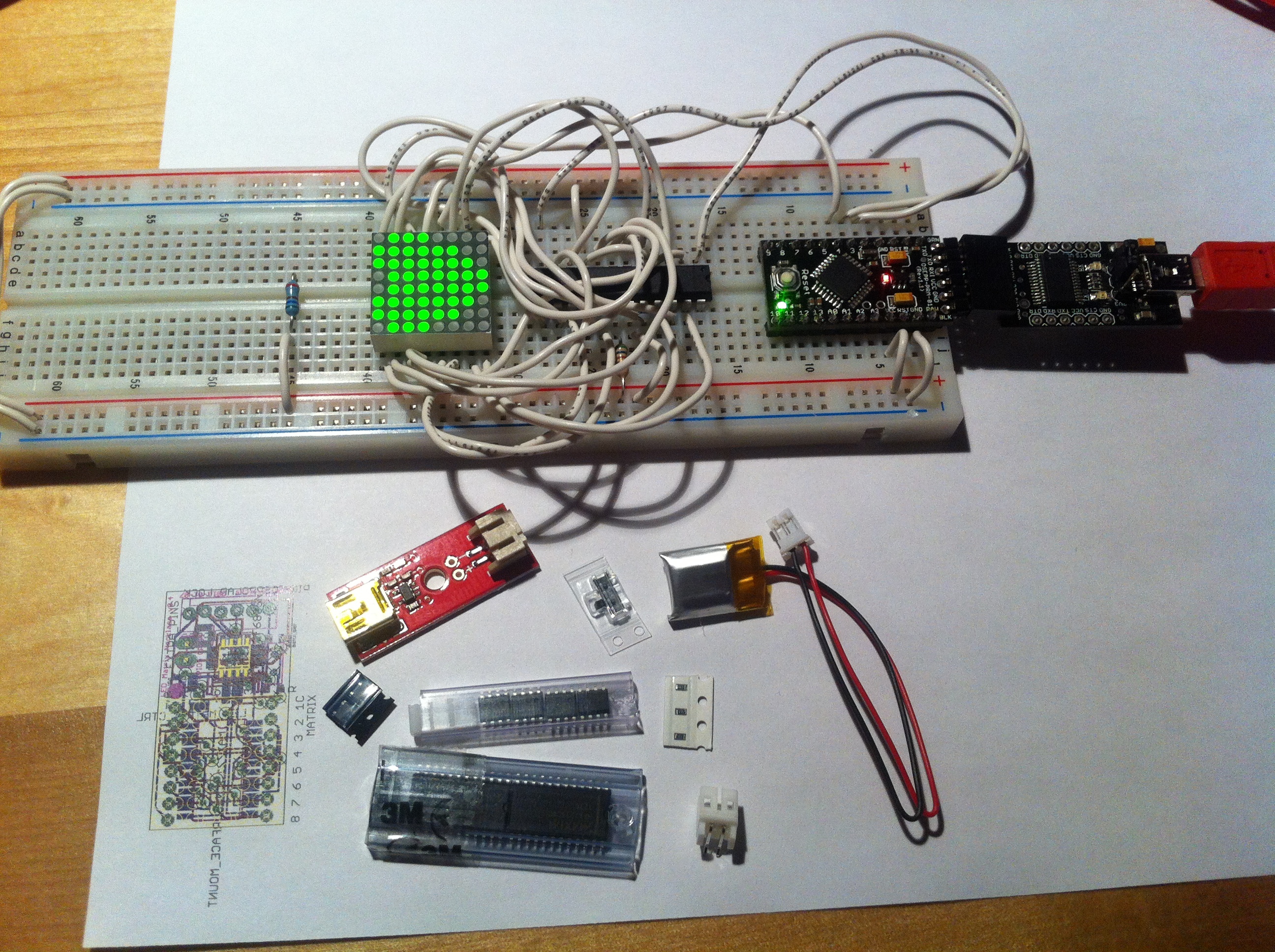 LED Matrix Necklace: Parts have arrived! Next to a printout of the first try on the PCB. The second try should show up this week...